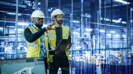 People in hard hats in front of HVAC equipment, reviewing diagnostics on tablet